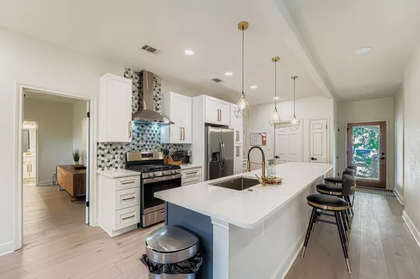 a kitchen with a refrigerator a stove and a sink with wooden floor