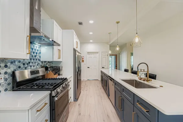 a kitchen with stainless steel appliances a sink stove and cabinets