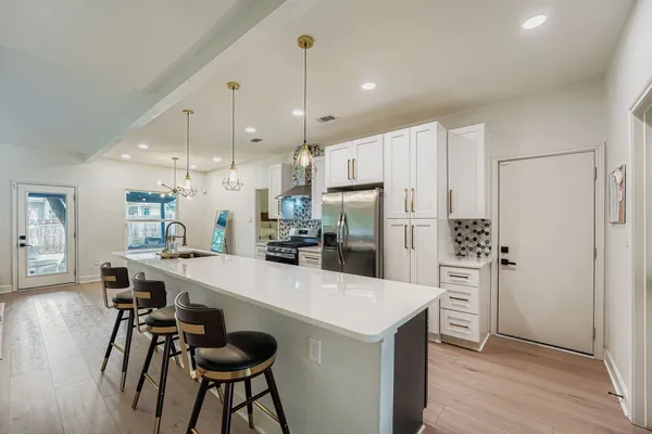 a kitchen with stainless steel appliances a dining table chairs refrigerator and microwave