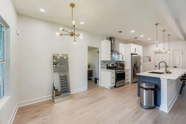 a kitchen with stainless steel appliances kitchen island granite countertop a refrigerator a oven a stove and a wooden floors