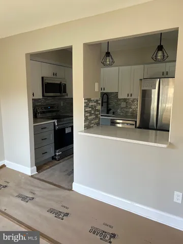 a kitchen with stainless steel appliances granite countertop a refrigerator a sink and white cabinets