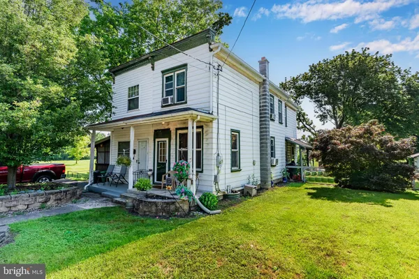 a view of a house with a yard and a large tree