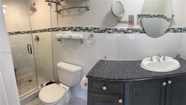 a bathroom with a granite countertop sink a mirror and a toilet