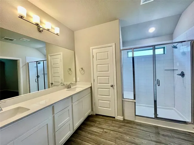 a spacious bathroom with a double vanity sink a large mirror and shower
