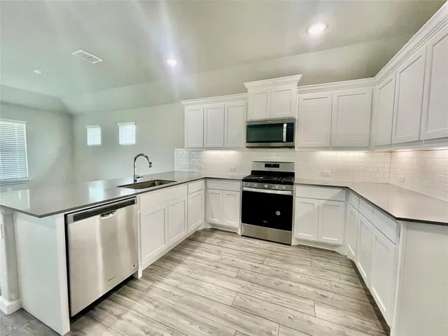 a kitchen with granite countertop a refrigerator and a stove top oven