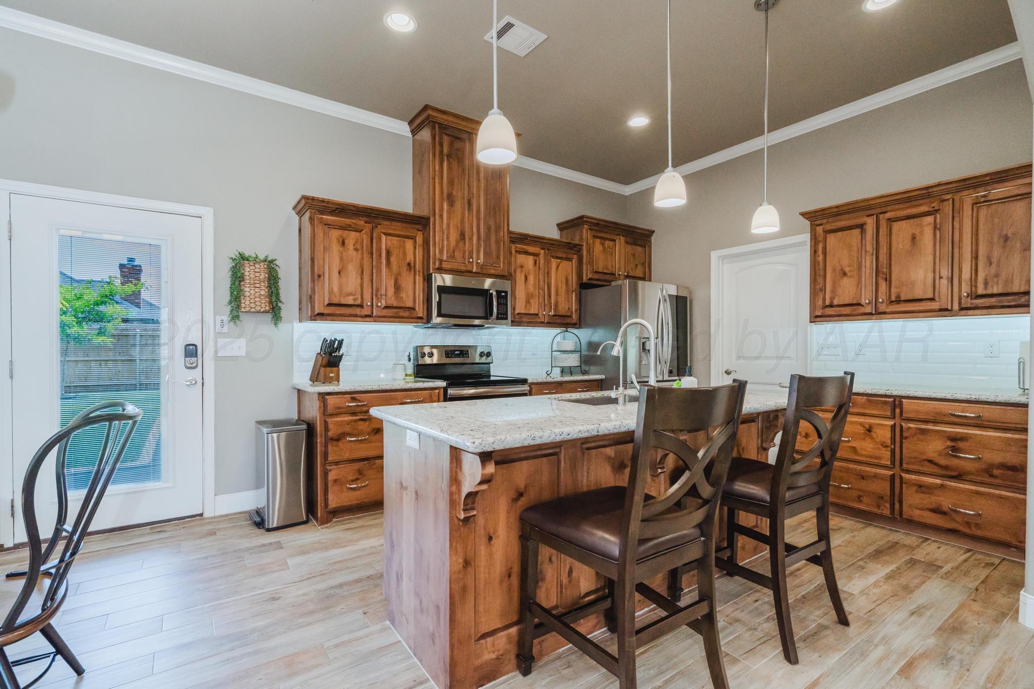 9011 Staten Island Amarillo, TX 79119 - Photo 6 of 17 a kitchen with stainless steel appliances granite countertop a stove top oven a sink a dining table and chairs with wooden floor