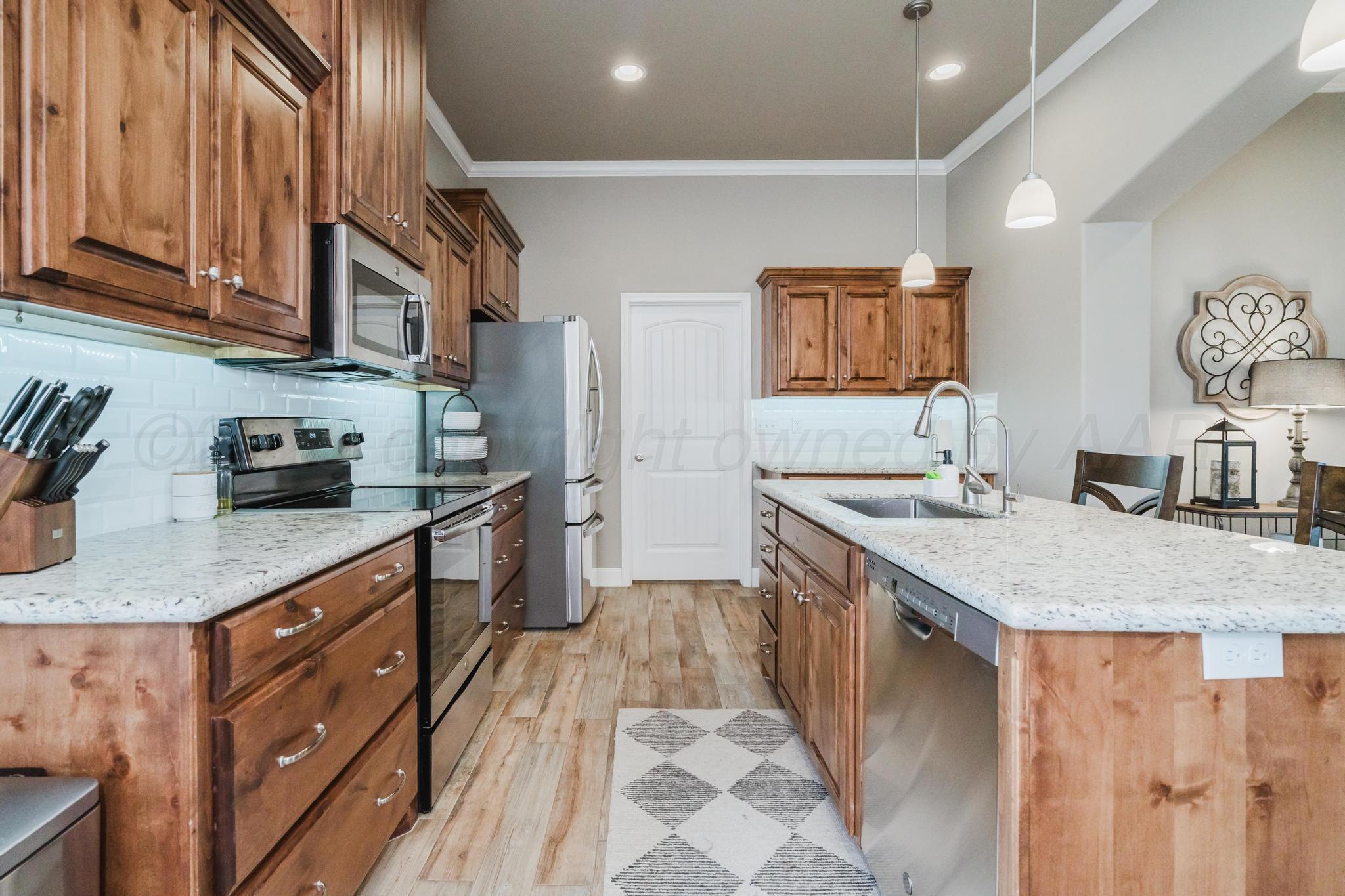 9011 Staten Island Amarillo, TX 79119 - Photo 7 of 17 a kitchen with stainless steel appliances granite countertop a sink and dishwasher stove with wooden cabinets