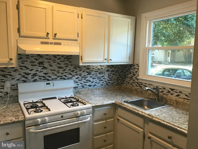 a kitchen with a stove a sink and a granite counter tops