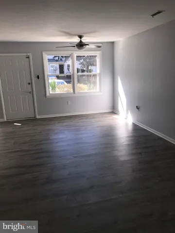 an empty room with wooden floor chandelier and windows