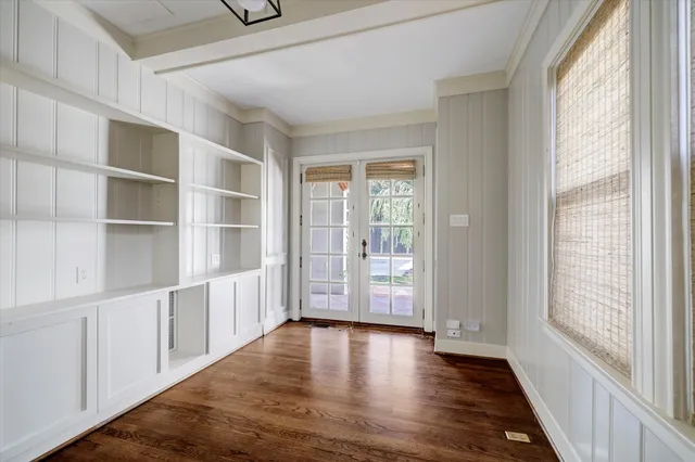 a view of an empty room with a window and wooden floor