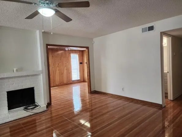 a view of an empty room with wooden floor and a fireplace