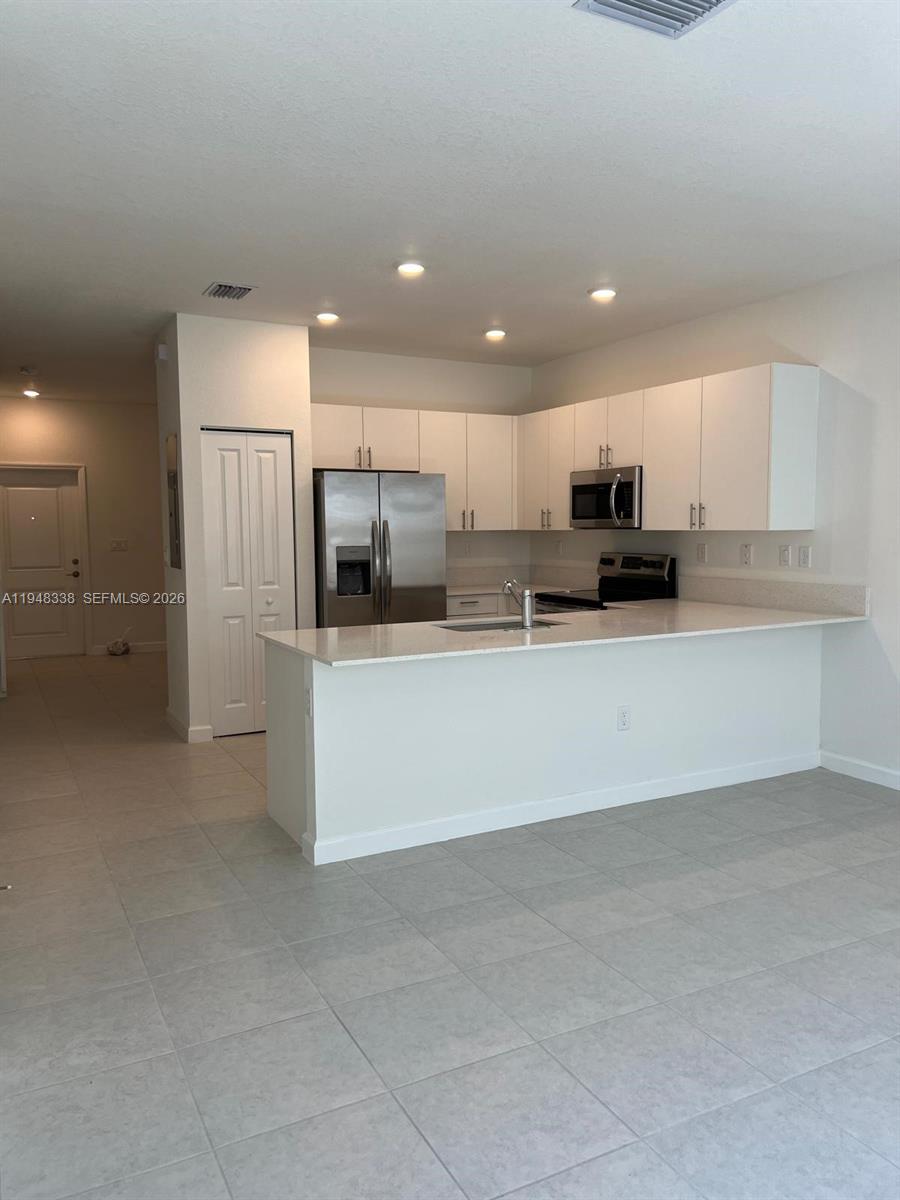 12908 Southwest 233rd Terrace Homestead, FL 33032 - Photo 16 of 23 a large kitchen with a large counter top stainless steel appliances and cabinets