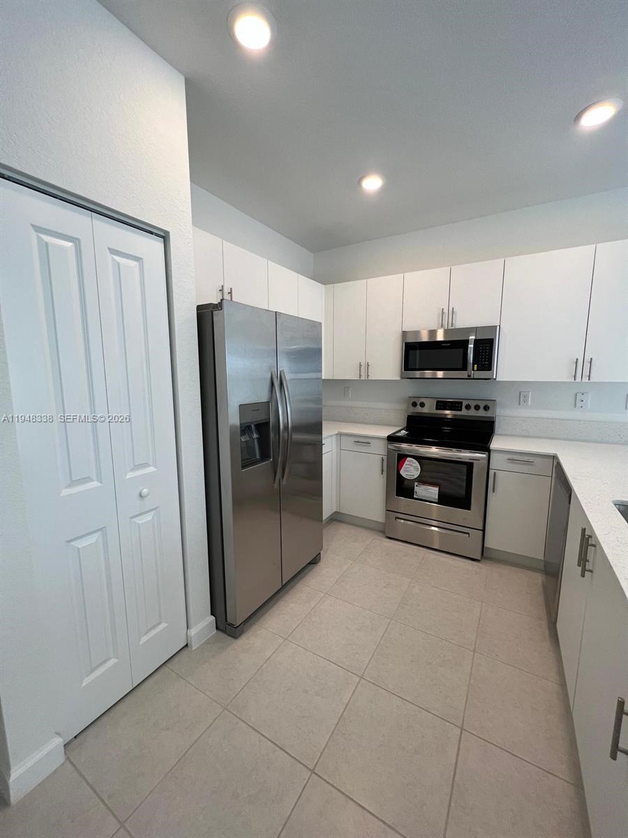 12908 Southwest 233rd Terrace Homestead, FL 33032 - Photo 21 of 23 a kitchen with stainless steel appliances a refrigerator sink and cabinets