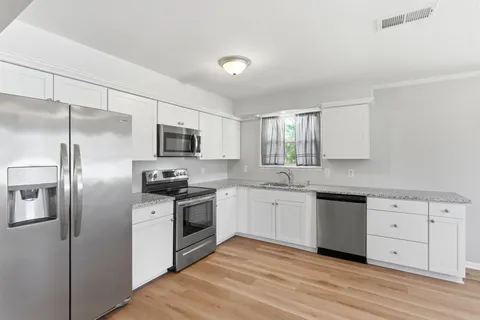 a kitchen with stainless steel appliances granite countertop a stove top oven a sink and dishwasher a refrigerator with wooden floor