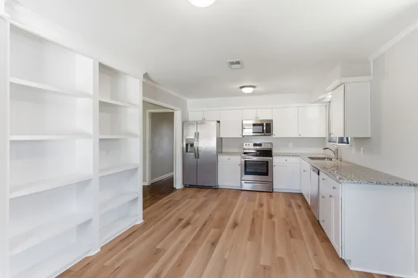 a large kitchen with a center island wooden floor stainless steel appliances and cabinets