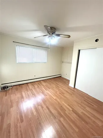 an empty room with wooden floor chandelier fan and windows