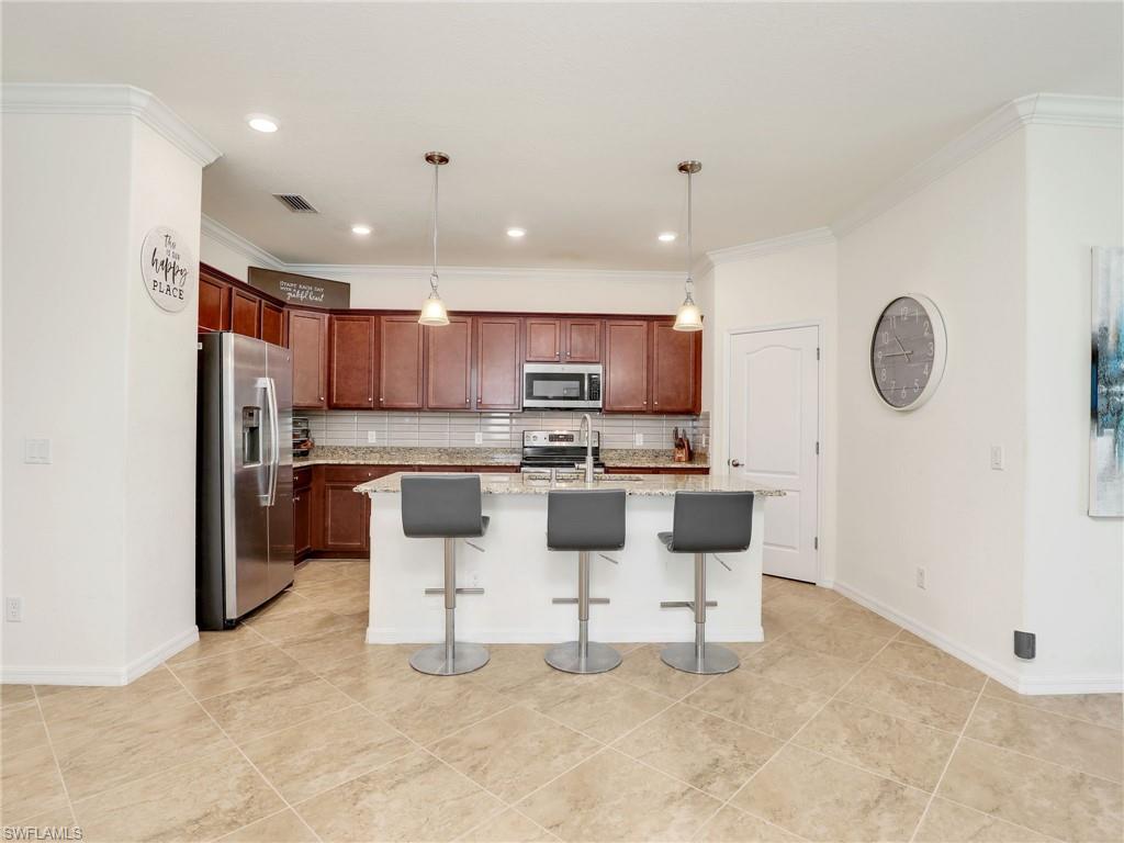 4212 Raffia Palm Circle Naples, FL 34119 - Photo 14 of 49 a kitchen with stainless steel appliances kitchen island granite countertop a stove a sink a microwave a refrigerator and cabinets