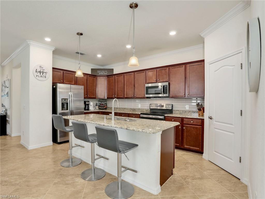 4212 Raffia Palm Circle Naples, FL 34119 - Photo 16 of 49 a kitchen with stainless steel appliances granite countertop a refrigerator a stove a sink a microwave and white cabinets