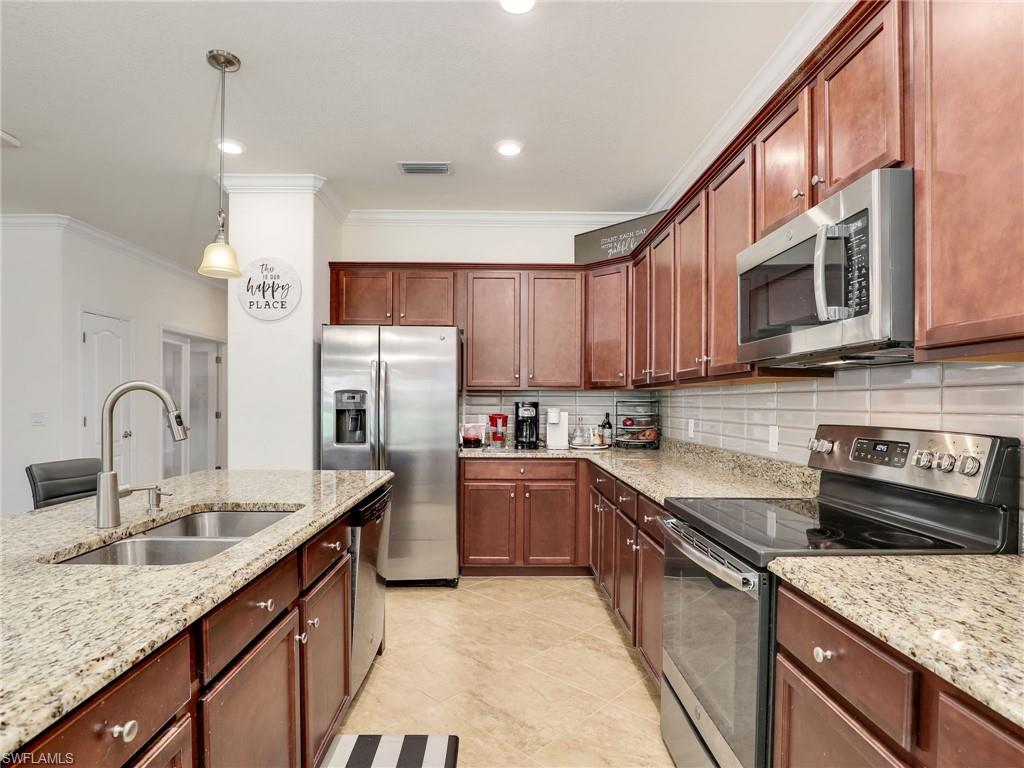 4212 Raffia Palm Circle Naples, FL 34119 - Photo 17 of 49 a kitchen with stainless steel appliances granite countertop a sink stove and refrigerator