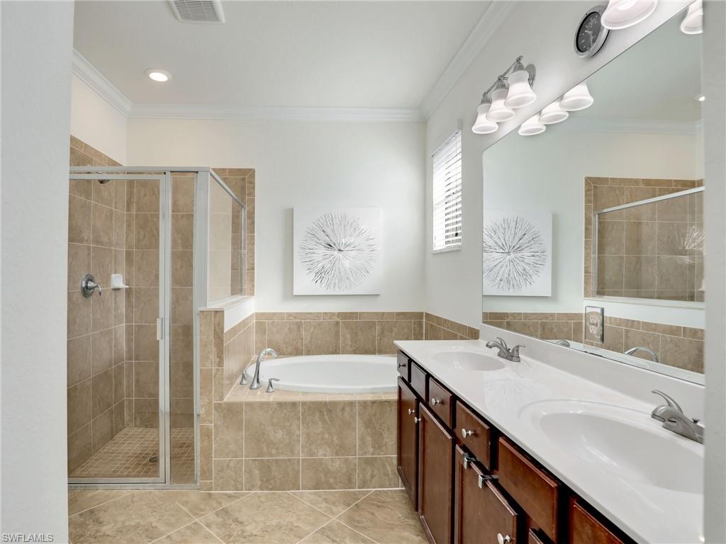 4212 Raffia Palm Circle Naples, FL 34119 - Photo 22 of 49 a bathroom with a tub a sink and mirror