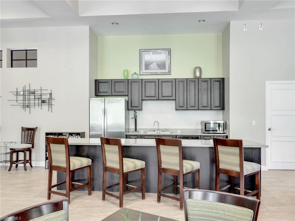 4212 Raffia Palm Circle Naples, FL 34119 - Photo 45 of 49 a dining hall with stainless steel appliances kitchen island granite countertop a dining table chairs and a refrigerator