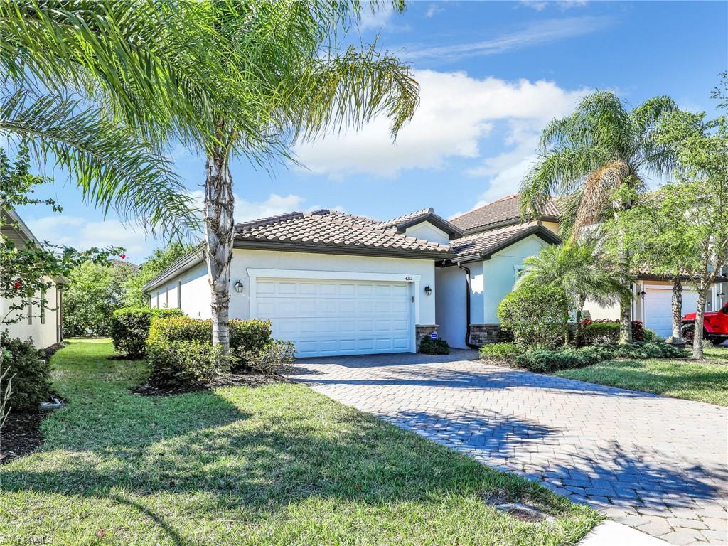 4212 Raffia Palm Circle Naples, FL 34119 - Photo 5 of 49 a front view of a house with a garden and tree
