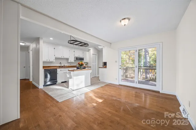 a large white kitchen with kitchen island a large window and a refrigerator