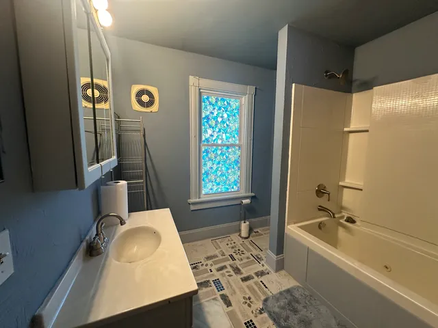 a bathroom with a tub sink and mirror