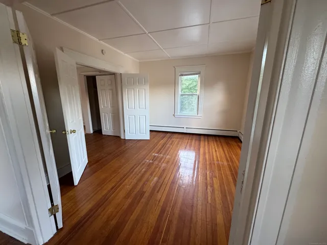 a view of empty room with wooden floor and fan