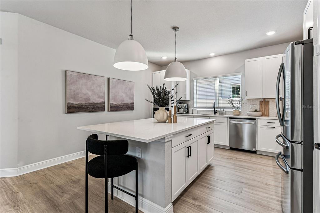 28748 Rambutan Drive Wesley Chapel, FL 33543 - Photo 13 of 37 a kitchen with stainless steel appliances kitchen island a table chairs in it and wooden floors