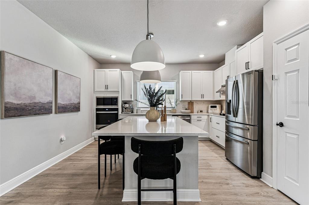28748 Rambutan Drive Wesley Chapel, FL 33543 - Photo 14 of 37 a kitchen with stainless steel appliances a dining table chairs refrigerator and cabinets