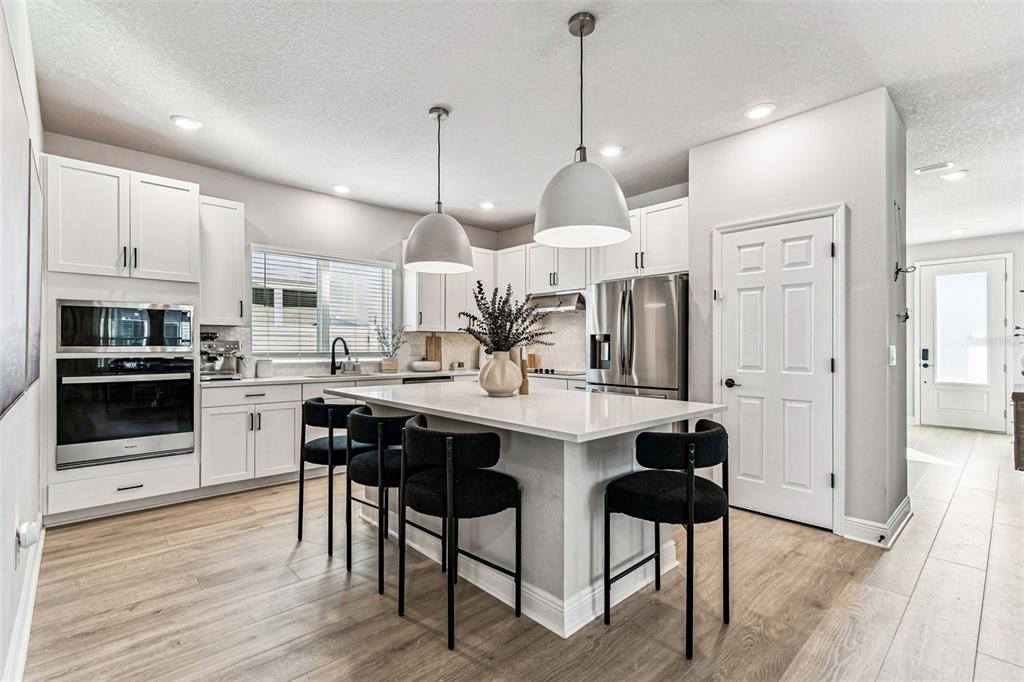 28748 Rambutan Drive Wesley Chapel, FL 33543 - Photo 15 of 37 a kitchen with stainless steel appliances kitchen island granite countertop a table chairs and a refrigerator