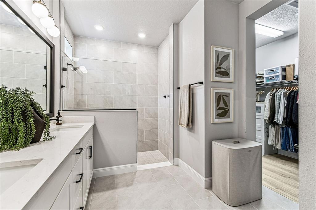 28748 Rambutan Drive Wesley Chapel, FL 33543 - Photo 24 of 37 a bathroom with a double vanity sink a large mirror and a shower