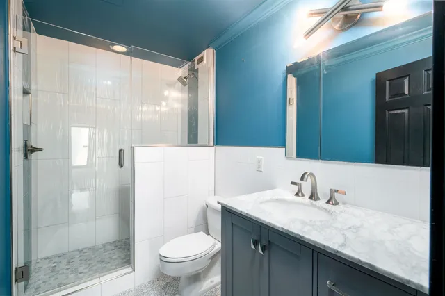 a bathroom with a granite countertop sink a toilet and shower