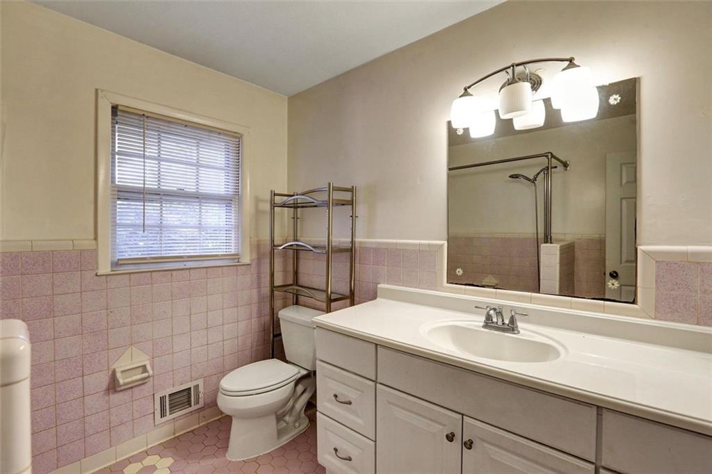 1266 Hickory Drive Southwest Lilburn, GA 30047 - Photo 37 of 49 a bathroom with a toilet a sink a mirror a window and vanity