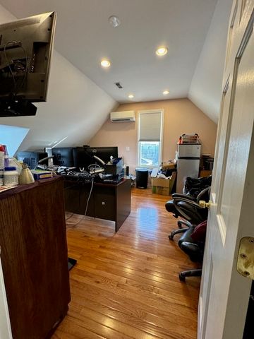 a kitchen with stainless steel appliances a refrigerator a stove a sink a couch and a dining table with wooden floor