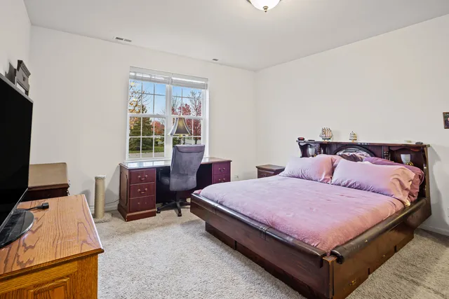 a bedroom with a bed and a flat tv screen on dresser
