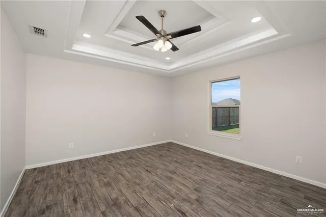 an empty room with wooden floor and ceiling fan