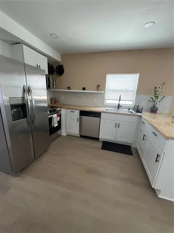 a kitchen with stainless steel appliances granite countertop a sink and dishwasher a stove top oven with white cabinets