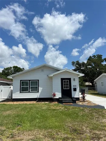 a view of a white house with a big yard and a large tree