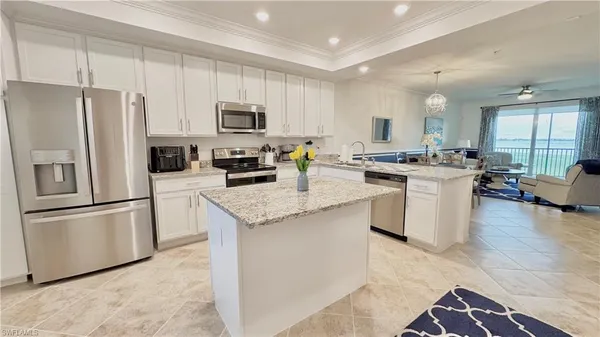 a kitchen with stainless steel appliances granite countertop a stove top oven a refrigerator a sink and white cabinets