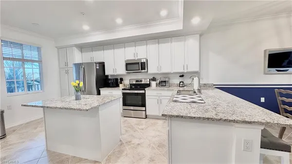 a kitchen with kitchen island granite countertop a sink counter top space appliances and cabinets