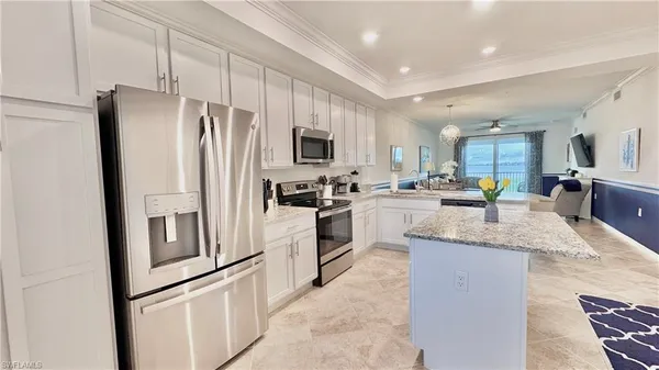 a kitchen with granite countertop a refrigerator a sink a stove a oven a dining table and chairs