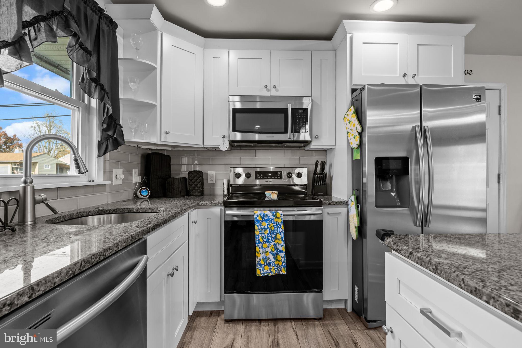 179 Crabtree Drive Levittown, PA 19055 - Photo 7 of 25 a kitchen with stainless steel appliances granite countertop a refrigerator a stove and a sink with wooden floor