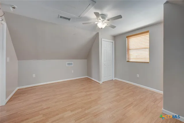 an empty room with wooden floor chandelier fan and windows