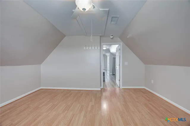 a view of an empty room with chandelier fan and a window