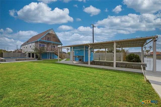 a view of a house next to a big yard with plants and large trees