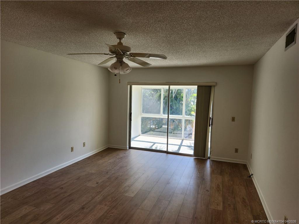 2950 Southeast Ocean Boulevard, Unit 311 Stuart, FL 34996 - Photo 6 of 16 an empty room with wooden floor fan and windows