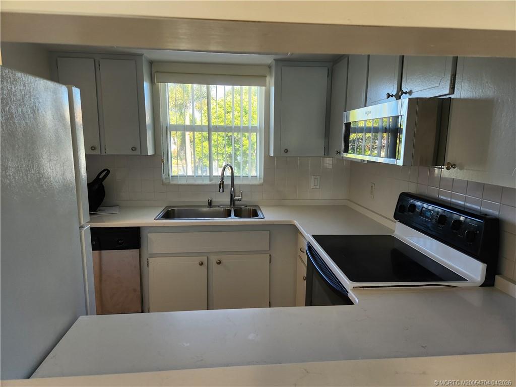 2950 Southeast Ocean Boulevard, Unit 311 Stuart, FL 34996 - Photo 10 of 16 a kitchen with a refrigerator sink and cabinets
