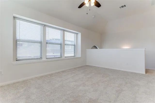 an empty room with a window and a ceiling fan